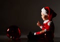 Smiling little baby boy toddler in red santa costume and cap is playing looking at christmas tree balls fir decoration Royalty Free Stock Photo