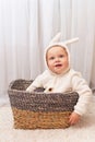 Smiling little baby in bunny easter costume sitting in the basket at home Royalty Free Stock Photo