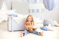 Smiling little blond girl hugs a teddy bear on the background of a decorative balloon. The child plays in the children`s room with