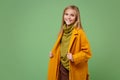Smiling little blonde kid girl 12-13 years old in yellow coat posing isolated on pastel green wall background children Royalty Free Stock Photo