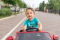 Smiling little boy driving by toy car. Active leisure and sports for kids. Portrait of happy little kid on the street. Funny cute Royalty Free Stock Photo