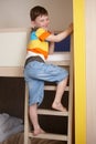 Smiling little boy going up the ladder of bunk bed