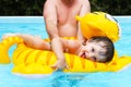 Smiling little boy on inflatable toy swimms with his father in p