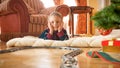 Cheerful smiling little boy looking on circle railroad under Christmas tree at houe living room. Child receiving