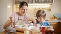 Smiling little boy with mother mixing ingredients in big bowl to make dough or biscuit. Children cooking with parents Royalty Free Stock Photo