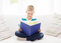 Smiling little boy reading book on couch Royalty Free Stock Photo