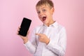 Smiling little boy showing at smartphone. Portrait of handsome male pointing with index finger at mockup cellphone, mobile, phone