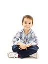 Smiling little boy sitting down on floor in jeans Royalty Free Stock Photo