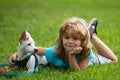 Smiling Little boy sitting on the grass with funny doggy. Happy child playing with dog on lawn. Royalty Free Stock Photo