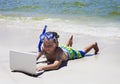 Smiling little boy using laptop lying on beach Royalty Free Stock Photo