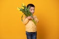 Smiling little boy on yellow studio background. Cheerful happy child with tulips flower bouquet Royalty Free Stock Photo