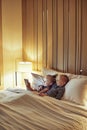 Smiling little brother and sister lying in bed watching videos Royalty Free Stock Photo