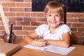 Smiling little caucasian girl sitting at a school desk st classroom. The child is doing homework. Preschool education, back to Royalty Free Stock Photo