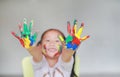 Smiling little cheerful girl showing her colorful hands and cheek painted in kids room. Focus at baby hands Royalty Free Stock Photo