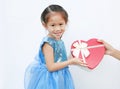 Smiling little child girl receiving red heart gift box isolated on white background. Concept Valentine`s Day Royalty Free Stock Photo