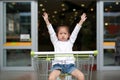 Smiling little child girl sitting in the trolley during family shopping in the market Royalty Free Stock Photo