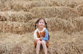 Smiling of little child girl and warm clothes sitting on pile of straw on a winter season