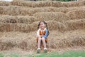 Smiling of little child girl and warm clothes sitting on pile of straw on a winter season