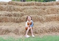 Smiling of little child girl and warm clothes sitting on pile of straw on a winter season