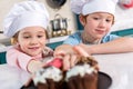 smiling little children in chef hats looking at delicious cupcakes Royalty Free Stock Photo