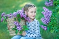Smiling little cute blonde child girl 4-9 years with a bouquet of lilac in the hands in jeans and shirt Royalty Free Stock Photo