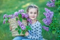 Smiling little cute blonde child girl 4-9 years with a bouquet of lilac in the hands in jeans and shirt Royalty Free Stock Photo