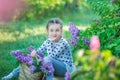 Smiling little cute blonde child girl 4-9 years with a bouquet of lilac in the hands in jeans and shirt Royalty Free Stock Photo