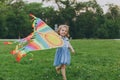 Smiling little cute child baby girl in denim dress walking, play with colorful kite and have fun in green park. Mother Royalty Free Stock Photo