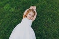 Smiling little cute child baby girl in light dress lie on green grass lawn, raise hands up in park. Mother, little kid Royalty Free Stock Photo