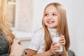 Smiling little daughter kepping milk glass near mother.