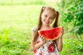 Smiling little girl with blue eyes eats a slice of watermelon Royalty Free Stock Photo