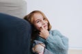 Smiling little girl in a blue sweater with rag doll sitting on the floor Royalty Free Stock Photo