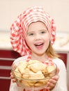 Smiling little girl in chef hat holding bowl with cookies Royalty Free Stock Photo