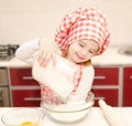 Smiling little girl with chef hat put flour for baking cookies Royalty Free Stock Photo