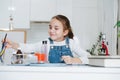 Smiling little girl doing home science project, reaching for crayons Royalty Free Stock Photo