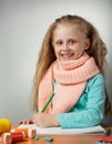 Smiling little girl draws at table, near inhaler on grey Royalty Free Stock Photo