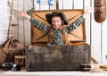 Smiling little girl with hands up sitting in big wooden chest Royalty Free Stock Photo