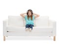 Smiling little girl in headphones sitting on sofa Royalty Free Stock Photo