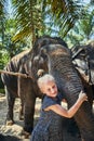 Smiling little girl hugging the trunk of an Asian elephant