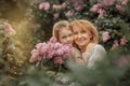 Smiling little girl hugs with her grandma in a lilac garden