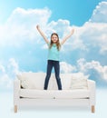 Smiling little girl jumping on sofa Royalty Free Stock Photo