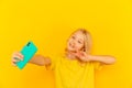 Smiling little girl kid showing blue screen of new popular mobile phone on light yellow background. Royalty Free Stock Photo