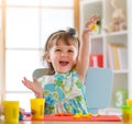 Smiling little girl is learning to use colorful play dough in a well lit room near window Royalty Free Stock Photo