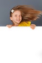 Smiling little girl looking behind a white board Royalty Free Stock Photo