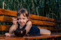 Smiling little girl lying on the bench with a blackberry in her hand. Royalty Free Stock Photo