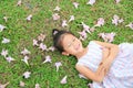 Smiling little girl lying on green grass with fall pink flower in the garden outdoor Royalty Free Stock Photo