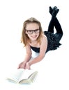Smiling little girl lying with an open book Royalty Free Stock Photo