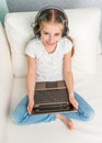 Smiling little girl with note book on sofa looks at camera Royalty Free Stock Photo