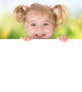 Smiling little girl peeking behind a board