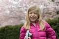 Smiling little girl with photo camera in cherry blossom park in spring